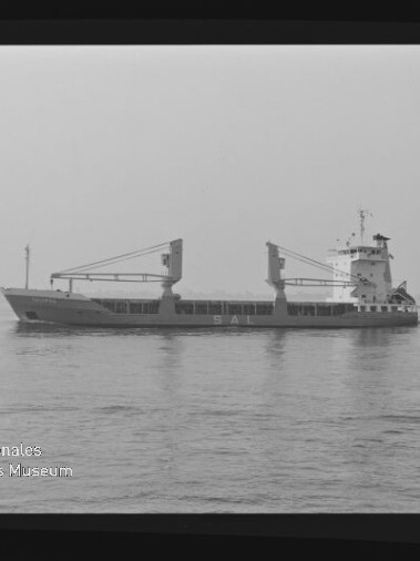 Frachtschiff mit zwei Ladekränen und achterem Aufbauten fährt seitlich auf ruhiger See; Schwarzweißaufnahme mit Museumslogo.
