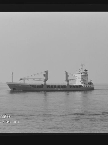 Frachtschiff mit zwei Ladekränen auf ruhiger See, Schwarzweißfoto mit Filmrand und Schriftzug AGFA APX 100.