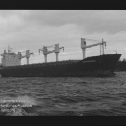 Frachtschiff CAMPANIA mit mehreren Ladekränen auf bewegter See, schwarzweißaufnahme mit sichtbarem Filmrand