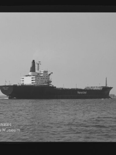 Großes Frachtschiff mit dem Schriftzug Hapag‑Lloyd fährt auf ruhiger See, schwarzweiß-Aufnahme mit Museumswasserzeichen.