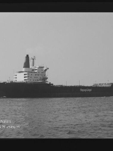Seitliche Aufnahme eines Hapag-Lloyd-Frachtschiffs auf ruhiger See in Schwarzweiß.