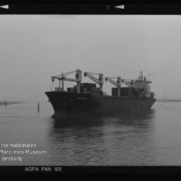 Containerfrachter mit Ladekränen auf ruhiger See, Schwarzweißfoto mit Museumswasserzeichen
