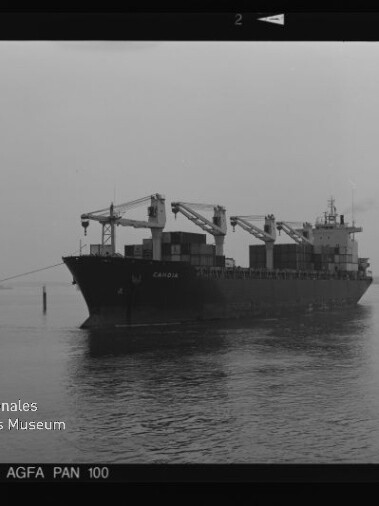 Containerfrachter mit Ladekränen auf ruhiger See, Schwarzweißfoto mit Museumswasserzeichen