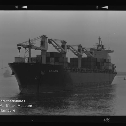Schwarzweißfoto eines Containerschiffs mit der Aufschrift CAMBIA, sichtbaren Bordkränen und gestapelten Containern, Museumswasserzeichen links unten.