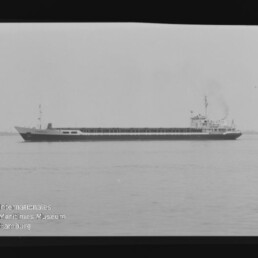 Langes Frachtschiff auf ruhiger See, schwarzweiß-Foto mit Internationales Maritimes Museum Hamburg Wasserzeichen unten links.