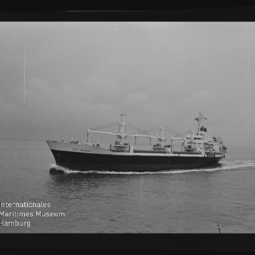 Schwarzweißaufnahme eines Frachtschiffs mit Ladekränen auf ruhiger See, links unten Wasserzeichen Internationales Maritimes Museum Hamburg