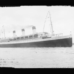 Historisches Passagierschiff mit drei Schornsteinen und geschmücktem Mast auf ruhiger See, Schwarzweiß.