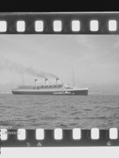 Ozeandampfer mit vier Schornsteinen auf ruhiger See, dargestellt als Fotonegativ mit Filmrand und Museumslogo.