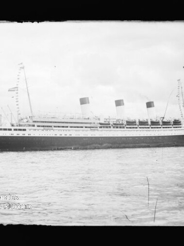 Seitenansicht eines historischen Passagierschiffs mit drei Schornsteinen auf ruhigem Wasser; Museumswasserzeichen unten links