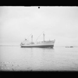 Großes Schiff mit zwei Masten und Wimpelketten auf ruhigem Meer, kleines Beiboot rechts; Museum-Wasserzeichen unten links.