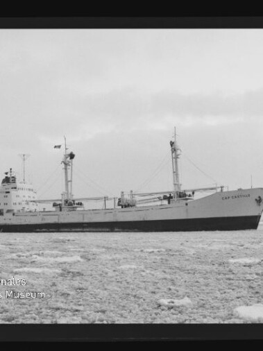 Großes Frachtschiff mit zwei Ladebäumen auf eisbedeckter See unter trübem Himmel, schwarz-weiß-Foto.