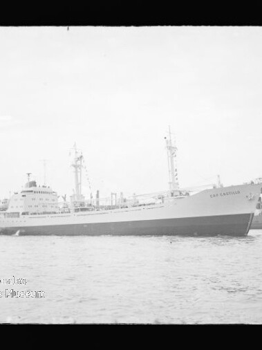 Großes Frachtschiff fährt auf ruhigem Wasser vor einem Industriehafen mit hohem Werftkran.