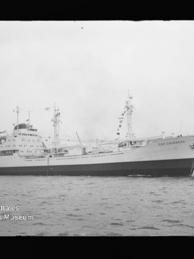 Passagier-/Frachtschiff Cap Colombie mit Masten und Ladebaum auf ruhigem Wasser, Schwarzweißaufnahme mit Museumswasserzeichen