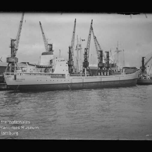 Frachtschiff am Kai unter mehreren Ladekränen in schwarzweiß; Museumslogo Maritimes Museum Hamburg unten.