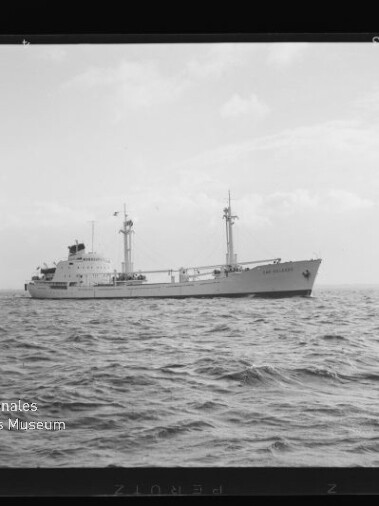 Schwarzweißaufnahme eines Frachtschiffs mit zwei Masten auf ruhiger See, Wasserzeichen Internationales Maritimes Museum Hamburg.