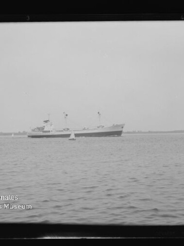 Schiff mit zwei Masten auf ruhigem Meer vor flachem Horizont, Boje im Vordergrund und Museumssiegel unten links.