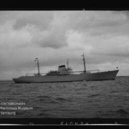Motorschiff mit Masten auf ruhiger See unter bewölktem Himmel; links unten Schriftzug Maritimes Museum Hamburg