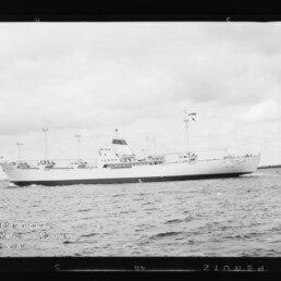 Weißes Passagierschiff im Profil auf ruhiger See, mit Schriftzug des Internationalen Maritimen Museums Hamburg unten links.