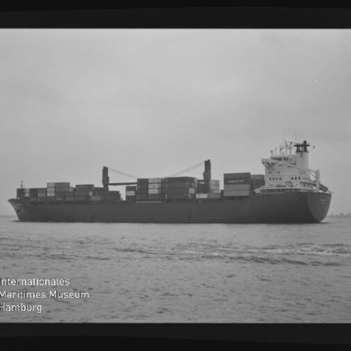 Containerschiff mit gestapelten Containern auf ruhigem Wasser, Schwarzweißaufnahme mit Museumslogo unten links.