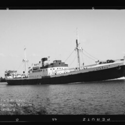 Frachtschiff ALEPPO in Profilansicht auf ruhigem Wasser, mit zwei Masten, Aufbauten und Museumslogo unten links.