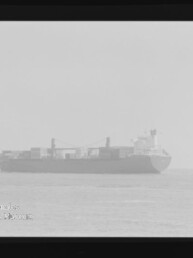 Frachtschiff mit Containern auf ruhiger See, leicht verschwommenes Schwarzweißfoto mit Filmrand und Museumslogo Internationales Maritimes Museum Hamburg