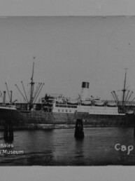 Schwarzweiß-Foto des Dampfschiffs Cap Norte mit Schornstein und Ladebäumen am Kai, mit Museumsstempel links unten.