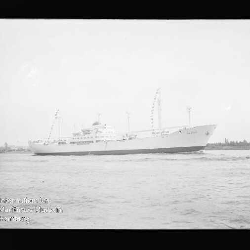 Weißes Schiff mit Masten und Wimpel fährt auf ruhigem Wasser vor flachem Ufer; Wasserzeichen: Maritimes Museum