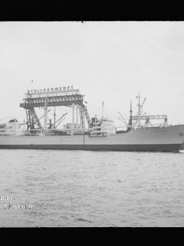 Großes Frachtschiff am Kai vor einem hohen Krangestell mit Beschriftung 
