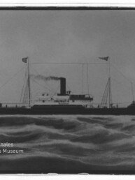 Dampfschiff mit rauchendem Schornstein und zwei Masten auf bewegter See; links unten Schriftzug 