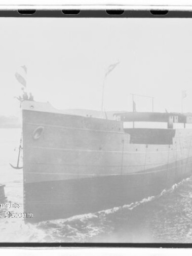 Bugansicht eines Frachtschiffs mit Flaggen auf ruhigem Wasser, schwarzweißes Archivfoto