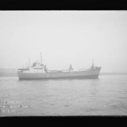 Graustufenfoto eines Frachtschiffs im Nebel auf ruhiger See, links unten das Wasserzeichen 