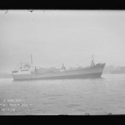Schwarzweißfoto eines Frachtschiffs seitlich auf ruhigem Wasser, mit Wasserzeichen Internationales Maritimes Museum Hamburg.