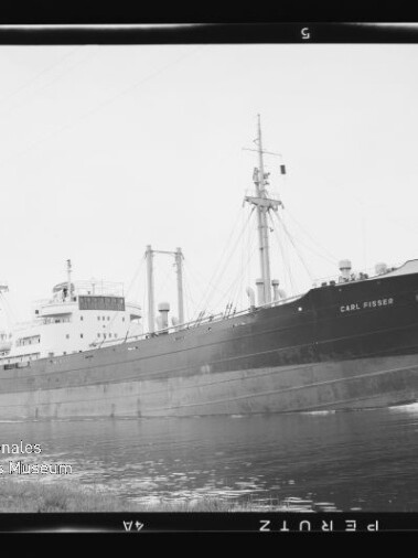 Frachtschiff Carl Fisser, seitliche Ansicht auf ruhigem Wasser, schwarzweißaufnahme mit Museumslogo links unten.