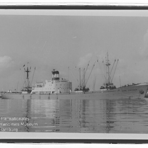 Frachtschiff mit Kränen und Masten auf ruhigem Wasser, Schwarzweißfoto mit Wasserzeichen des Maritimen Museums Hamburg.