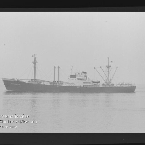 Frachtschiff im Seitenprofil auf ruhigem Meer mit mehreren Ladebäumen, Schornstein und Brückenaufbau.