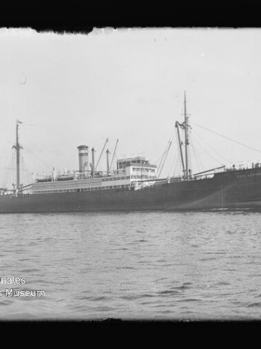 Großes historisches Dampfschiff mit Schornstein, Masten und Ladegeschirren in ruhigem Wasser, Seitenansicht.