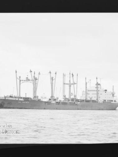 Frachtschiff mit mehreren Ladekränen und Masten auf ruhiger See, Seitenansicht vor flachem, flachem Horizont
