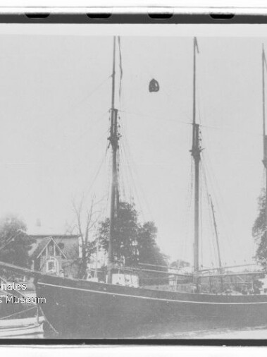 Dreimastiger Segler am Ufer mit kleinem Beiboot, Bäume und Haus im Hintergrund und Museumsstempel unten links.