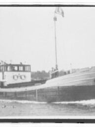 Kleiner Frachter mit Bug rechts, Steuerhaus und Mast, vor Ufer; Wz. Maritimes Museum Hamburg