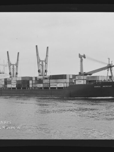 Containerschiff mit Ladekränen und gestapelten Containern auf ruhiger See, Schwarzweißfoto mit Museumswasserzeichen.
