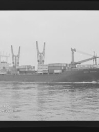 Containerschiff mit Containern und Deckkränen fährt über ruhiges Wasser; Wasserzeichen: Maritimes Museum Hamburg