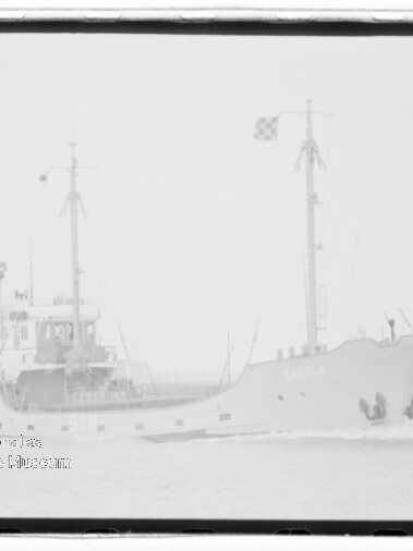 Schiff mit zwei Masten und Flagge fährt auf ruhiger See; Wasserzeichen unten links.