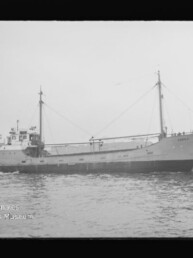 Frachtschiff mit zwei Masten fährt auf ruhigem Wasser; links unten Wasserzeichen des Internationalen Maritimen Museums Hamburg.