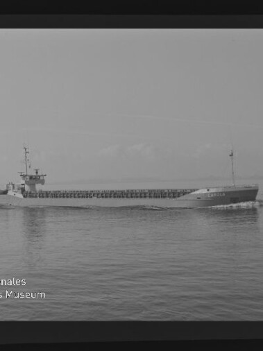 Schwarzweiß-Foto eines Frachtschiffs in Seitenansicht auf ruhigem Meer; Filmrand und Museumswasserzeichen sichtbar.
