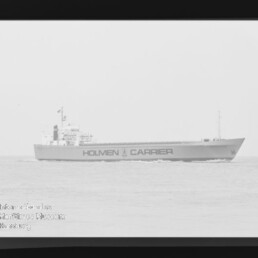 Seitenansicht eines Frachtschiffs mit der Aufschrift HOLMEN CARRIER, das ruhig auf dem Meer fährt.
