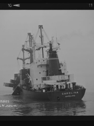 Schwarzweiß-Foto eines Frachtschiffs CAROLINA (Hamburg) mit Ladekränen auf ruhiger See.