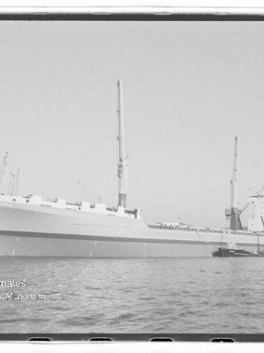 Großes Frachtschiff am Hafenpier mit Ladekränen, Schwarzweißaufnahme; Stempel Internationales Maritimes Museum Hamburg.