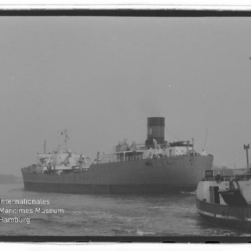 Großes Frachtschiff mit markantem Schornstein und Schlepper im Vordergrund, Wasserzeichen des Maritimen Museums Hamburg.