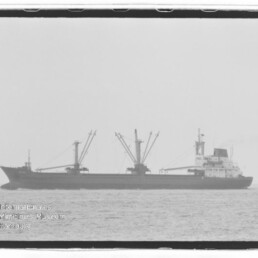 Frachtschiff mit drei Ladekränen auf ruhiger See; Wasserzeichen Internationales Maritimes Museum Hamburg.