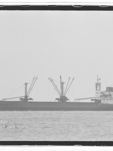 Frachtschiff mit drei Ladekränen auf ruhiger See; Wasserzeichen Internationales Maritimes Museum Hamburg.